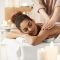Young beautiful african girl smiling enjoying massage with closed eyes in spa salon.