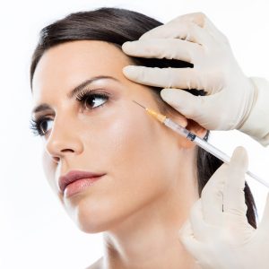 Beautiful young woman getting botox cosmetic injection in her fa Portrait of beautiful young woman getting botox cosmetic injection in her face over white background.